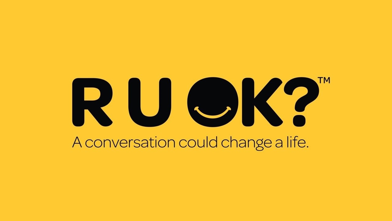 The words "R U OK? A conversation could change a life." are written in black over a yellow background.