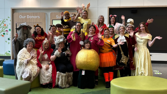 A large group of teachers wearing a variety of book themed costumes.
