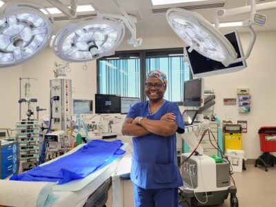 A nurse in scrubs standing in an operating theatre.