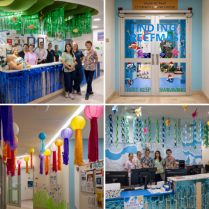 A decorated hospital ward entrance with blue streamers suggesting water, cut out fish shapes coloured in by children on the walls and staff in scrubs smiling.