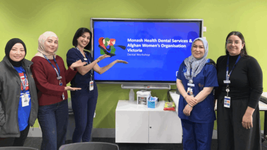 Five women, some of them wearing head scarves, smile for a photo at a dental information session.