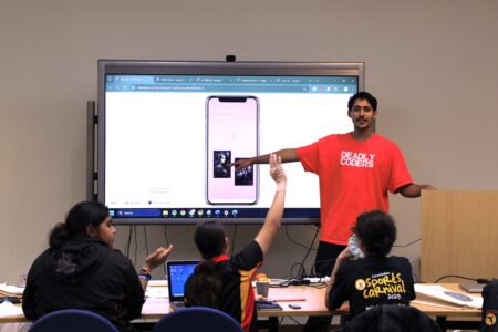 Photo of a Deadly Coders instructor demonstrating a student's prototype app to a group of students.