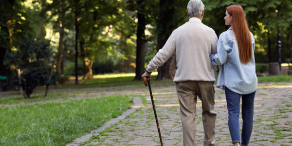 Senior man with walking cane and young woman in park, back view. Space for text Senior man with walking cane and young woman in park, back view. Space for text