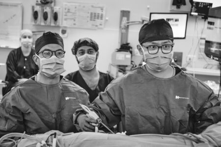 A black and white photograph of surgeons wearing gowns, masks and caps as they operate to remove a kidney from a live donor.