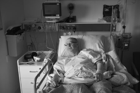 A man in a hospital gown lying in a hospital bed following surgery.